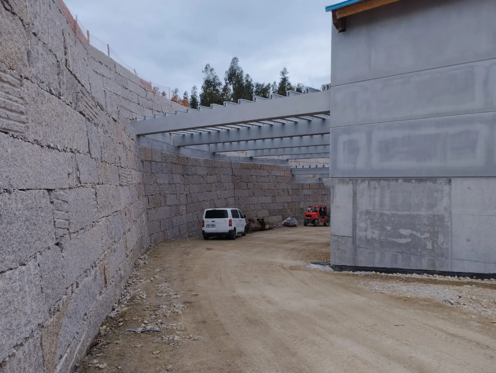 Muro de cachote de gran desarrollo junto a una nave industrial